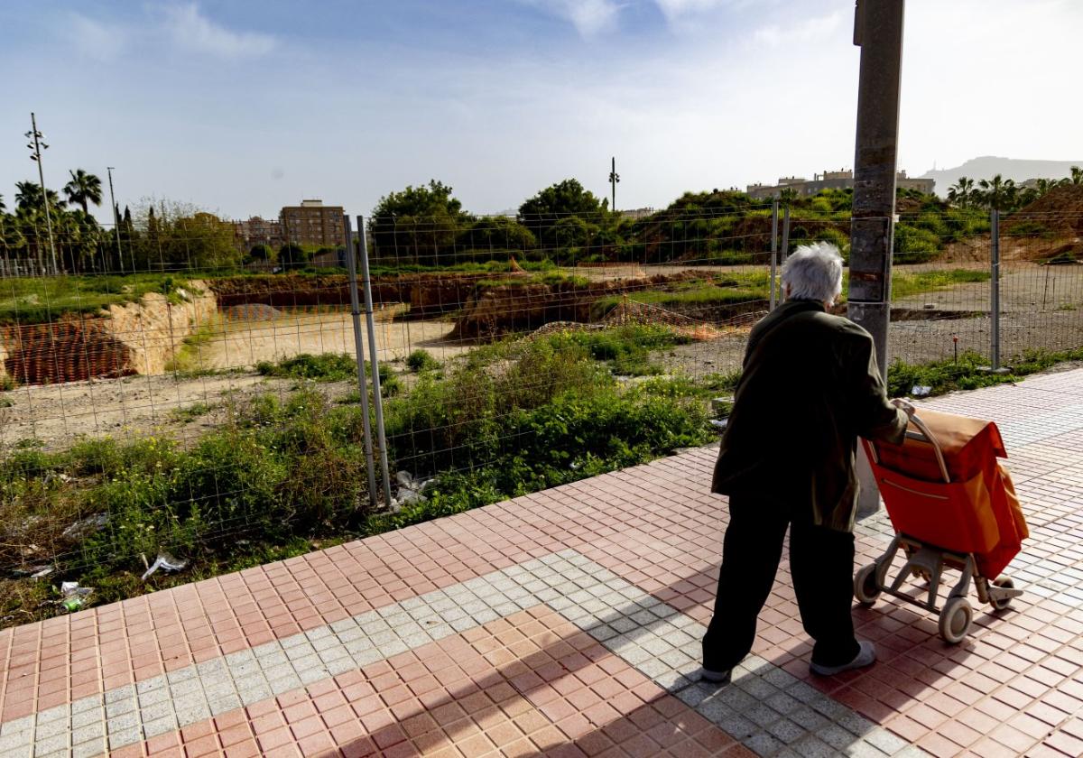 Una señora pasea con el carrito de la compra frente a los terrenos de la escuela infantil.