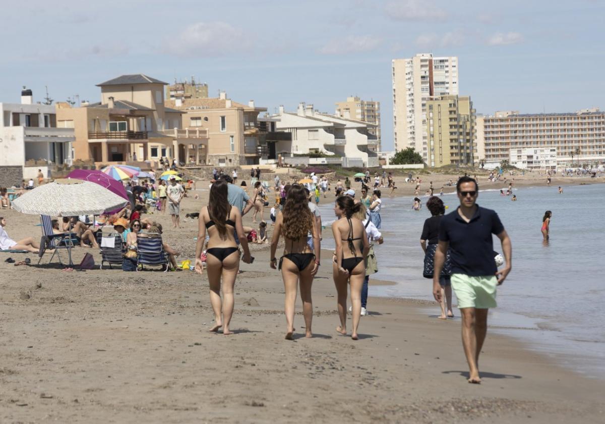 Una de las playas de La Manga del Mar Menor repleta de bañistas, que aprovechan el soleado día para darse los primeros baños.