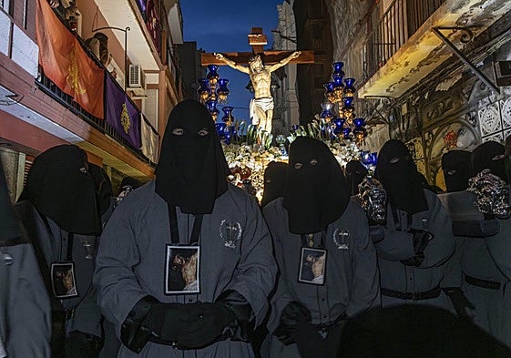 Un grupo de portapasos, con sus escapularios y capuces negros, descansa en la calle del Aire en su salida, ayer, junto el Cristo de los Mineros.