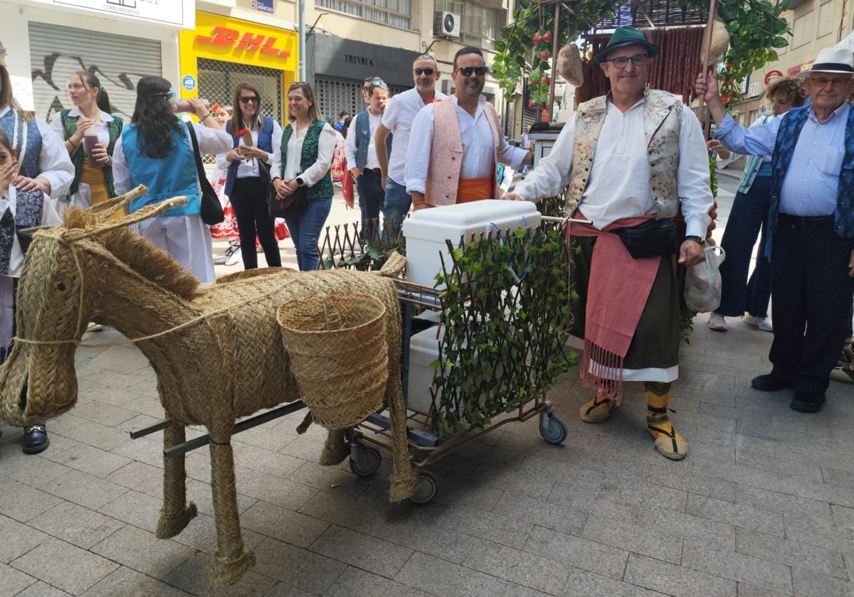 Un grupo de participantes posa junto a un burro de esparto que simula tirar de su carro.