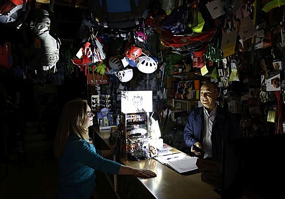 Los dueños de la tienda de deportes Nortes, este lunes en Murcia, alumbran el mostrador con una linterna.