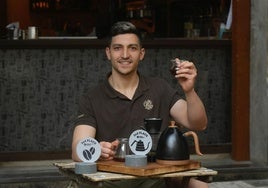 Nahuel Cian, en la terraza de CaféLab, en Murcia, tomando un café y mostrando los dos premios obtenidos este año.