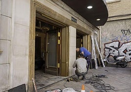 Dos instaladores cambian la verja de acceso a la sala.