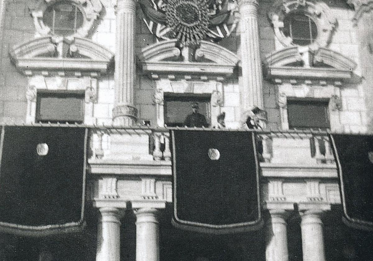 Instante justo en el cual el Rey Alfonso XIII sale al balcón del Palacio, adornado con banderas de España y Reino Unido, para saludar al pueblo de Cartagena.