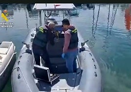 Dos guardias civiles inspeccionan una de las lanchas afectadas por robos este año en Mazarrón.