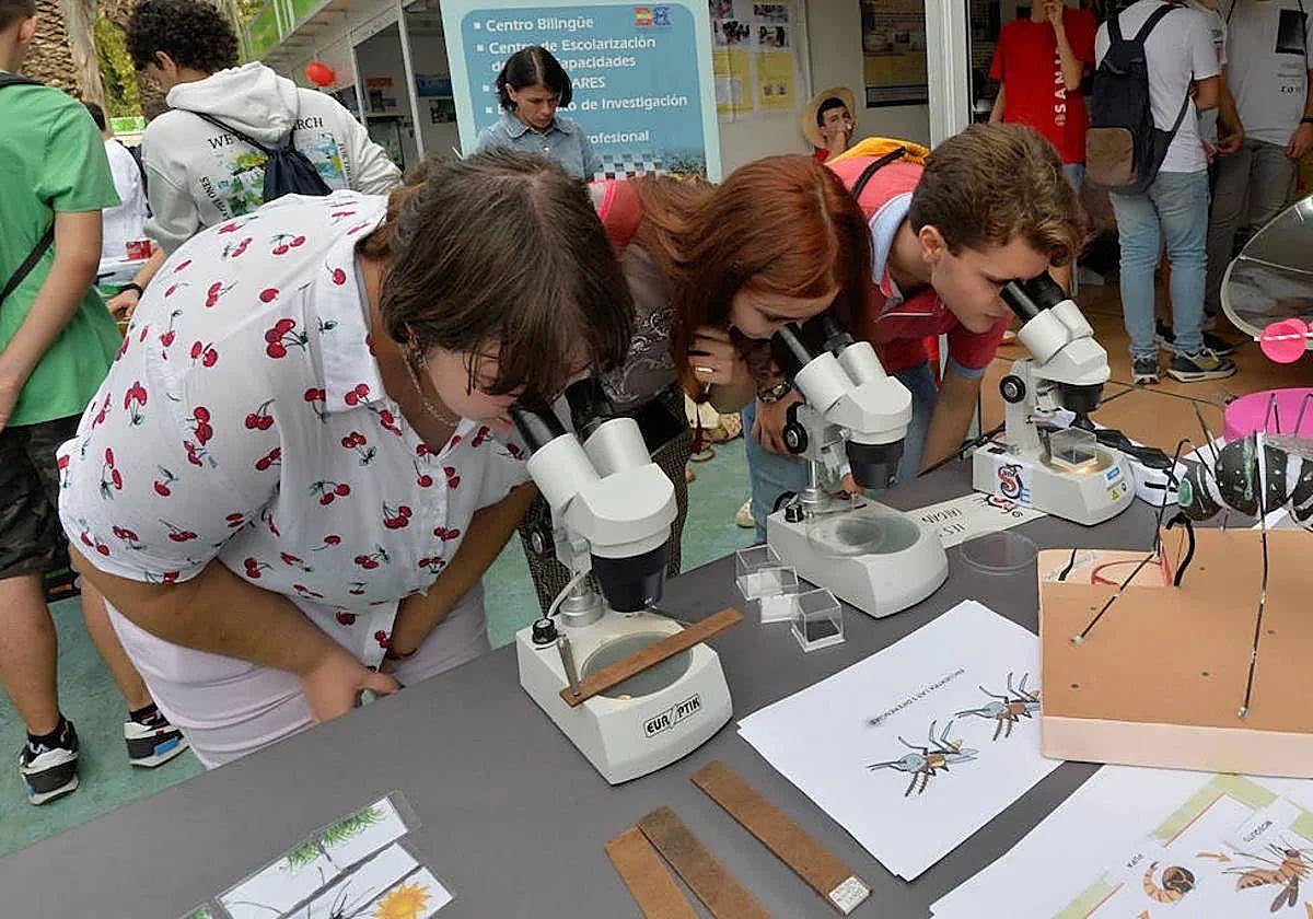 Tres personas miran por el microscopio, en una imagen de archivo.