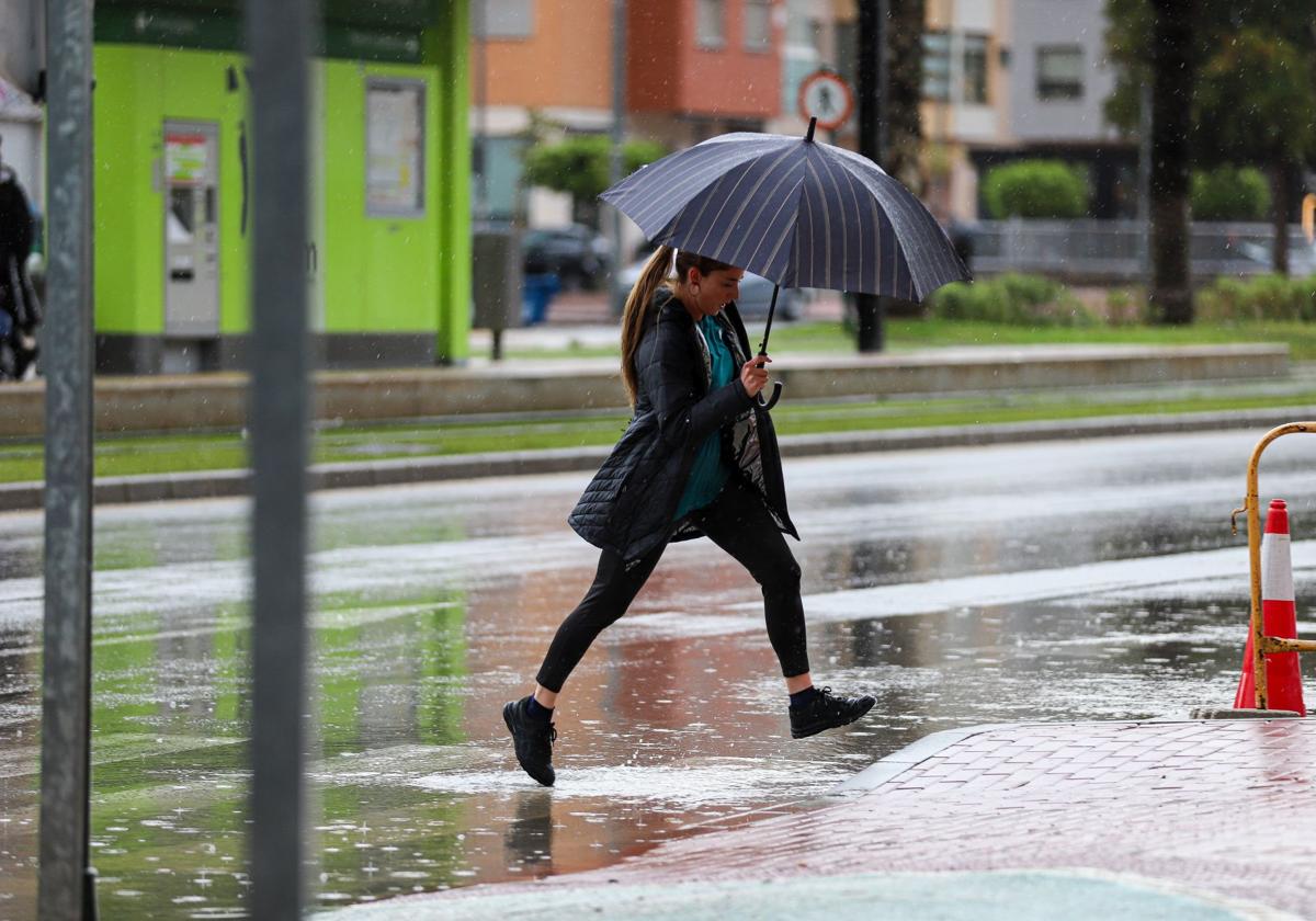 Una mujer salta para evitar un charco en Murcia.