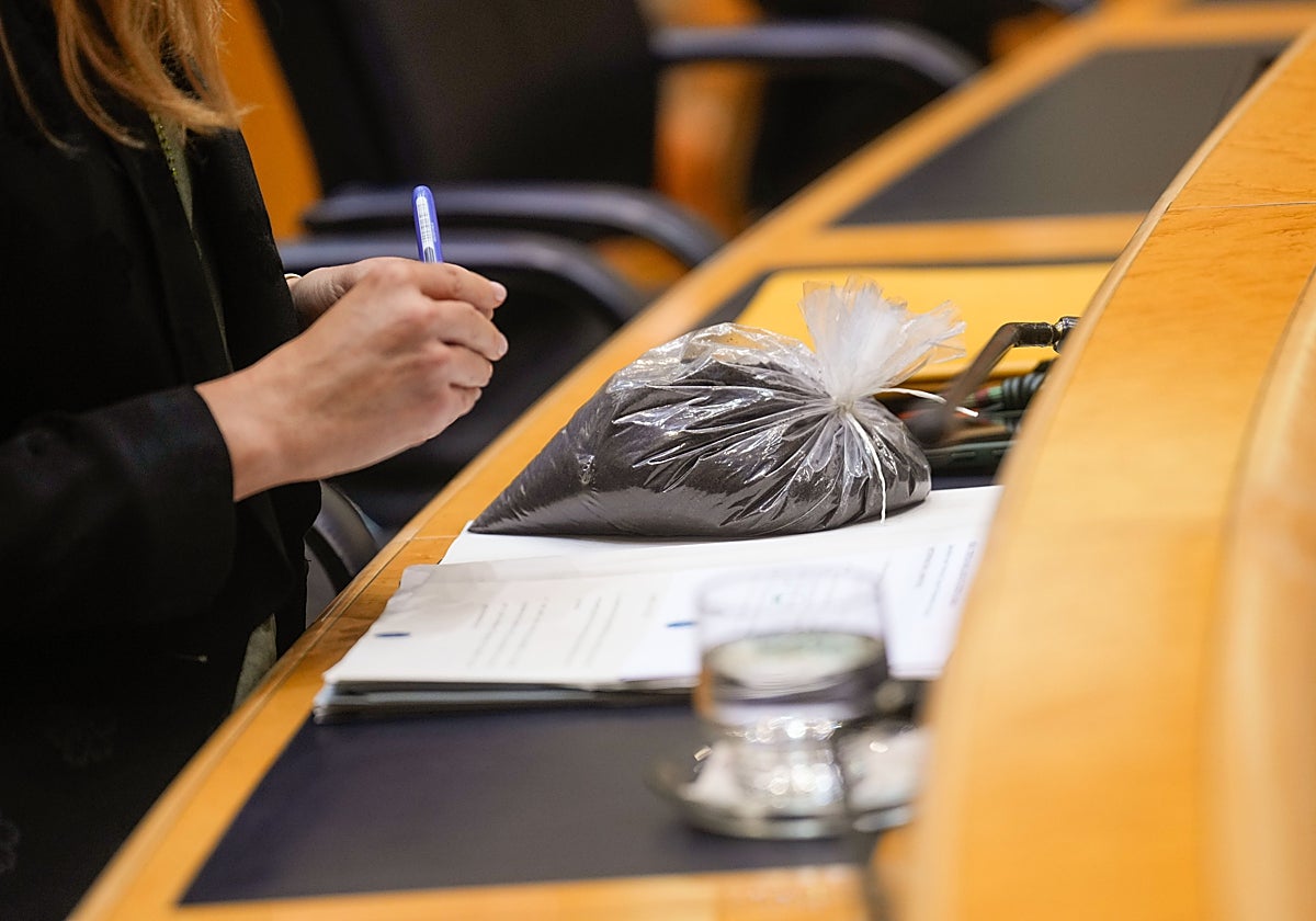 La bolsa con los estériles mineros depositada frente a la ministra Aagesen por el senador Bernabé, este martes.