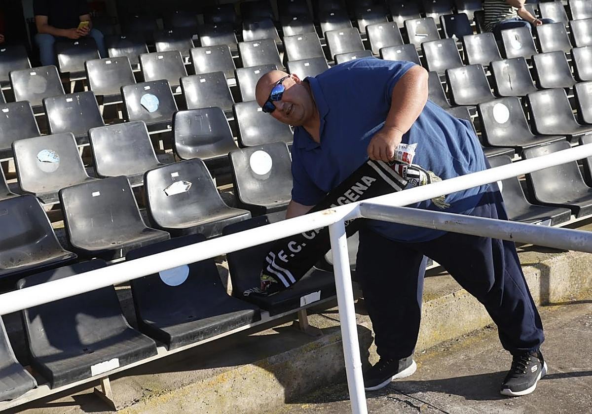 Un aficionado del Efesé limpia su asiento con la bufanda en el partido ante el Racing.