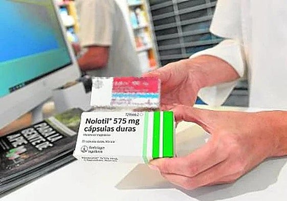 Un farmacéutico muestra unas cajas de medicamentos.