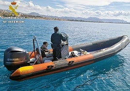 Un agente de la Guardia Civil, maneja la lancha, junto al detenido.
