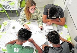 Tres menores del centro Rosa Peñas de la pedanía murciana de Santa Cruz hacen los deberes junto a una de las educadoras, en una imagen de archivo.