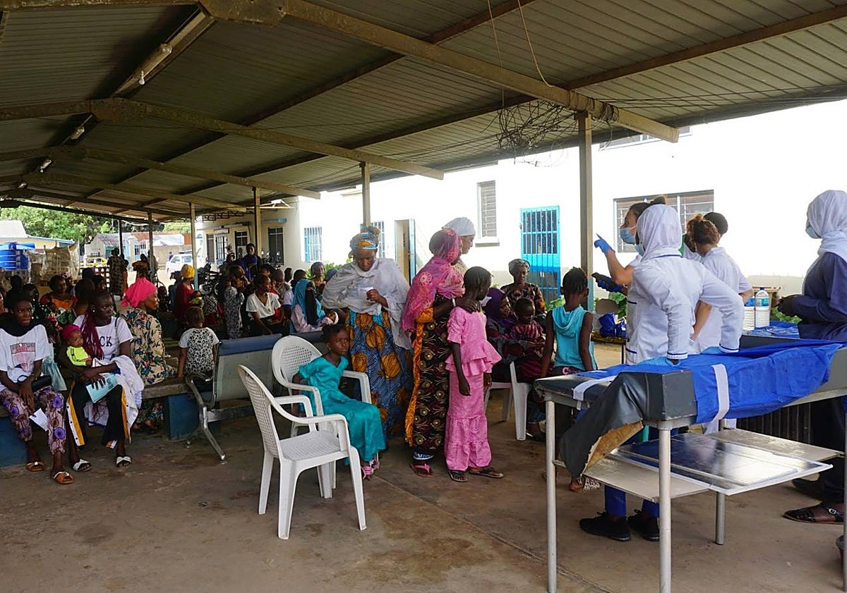 Imagen principal - En la primera foto, madres aguardan con sus hijos su turno para ser atendidos en Faji Kunda, Gambia, en 2023. En la segunda imagen, el equipo de Pediatría Solidaria en 2024, en uno de sus trayectos en el país africano. En la tercera, las pediatras Laura Sanz y Ana Jaén atienden a una paciente en el consultorio rural de Kandong.