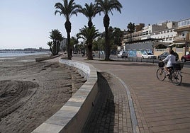 Una mujer cruza en bicicleta el paseo marítimo de Santiago de la Ribera, cerca del antiguo Hotel y hospital Los Arcos. La foto es de archivo.