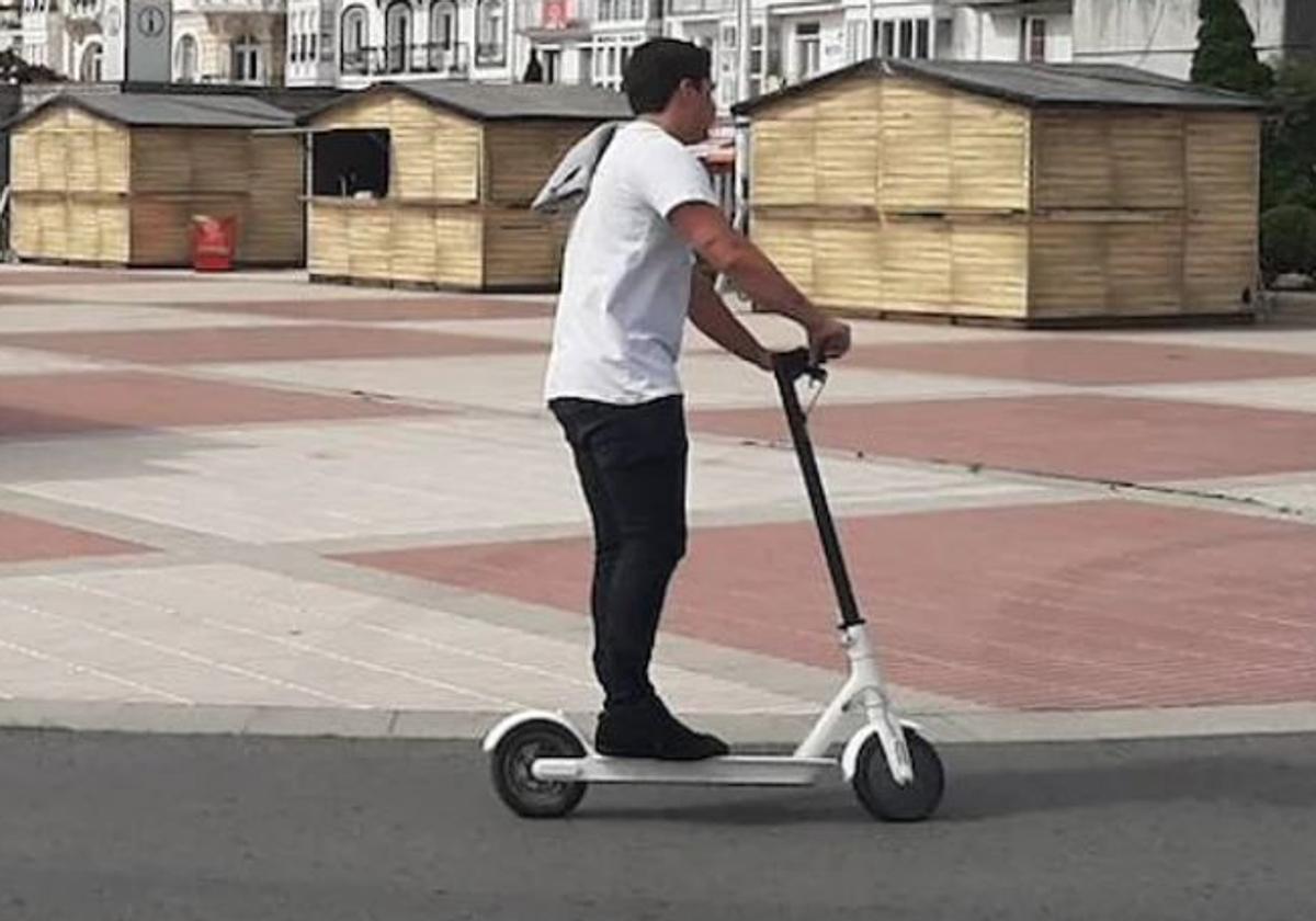 Un usuario de patinete circula por una carretera.