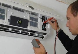 Imagen de archivo de un técnico instalando un climatizador en una vivienda.