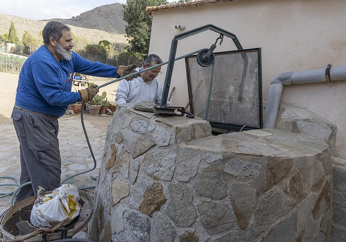 Dos vecinos de Campillo de Adentro extraen agua de su pozo.