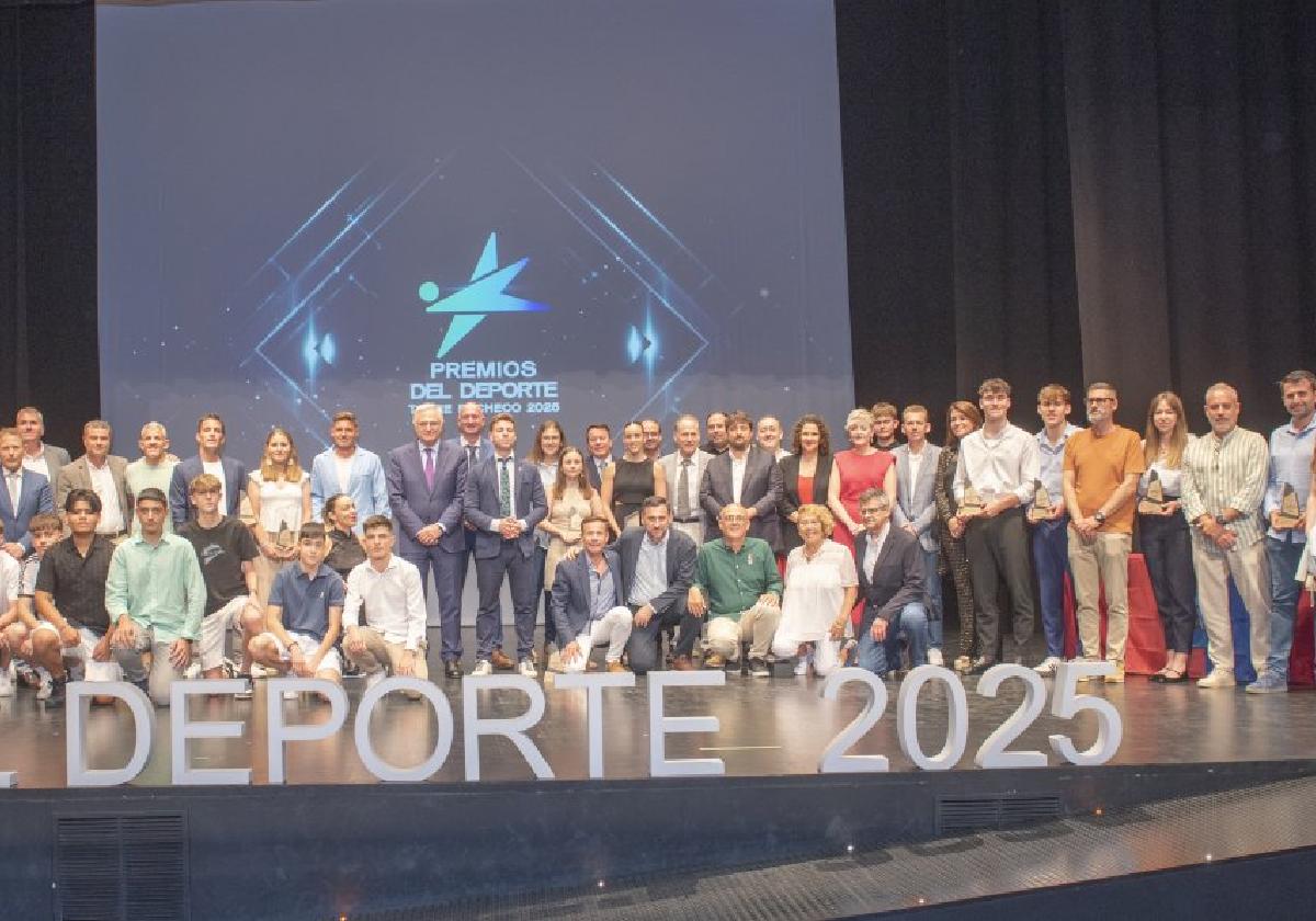 Foto de familia de premiados y autoridades en el escenario del CAES.