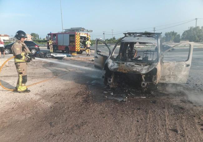 Un bombero refresca el vehículo afectado tras controlar las llamas.