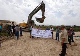 Una pala retroexcavadora pasa junto a los vecinos concentrados en la rambla de La Torrecilla donde se construye la plataforma del AVE.