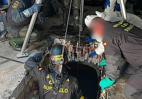 Un agente de la Guardia Civil se introduce en el depósito de aceite donde se encontraron los restos humanos.