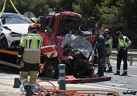 Bomberos y agentes de la Guardia Civil, junto al camión grúa implicado en el accidente mortal.