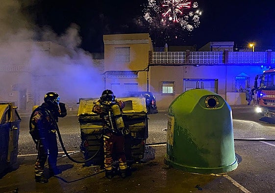 Bomberos apagan un contenedor en el barrio de Los Mateos, en una imagen de este lunes.