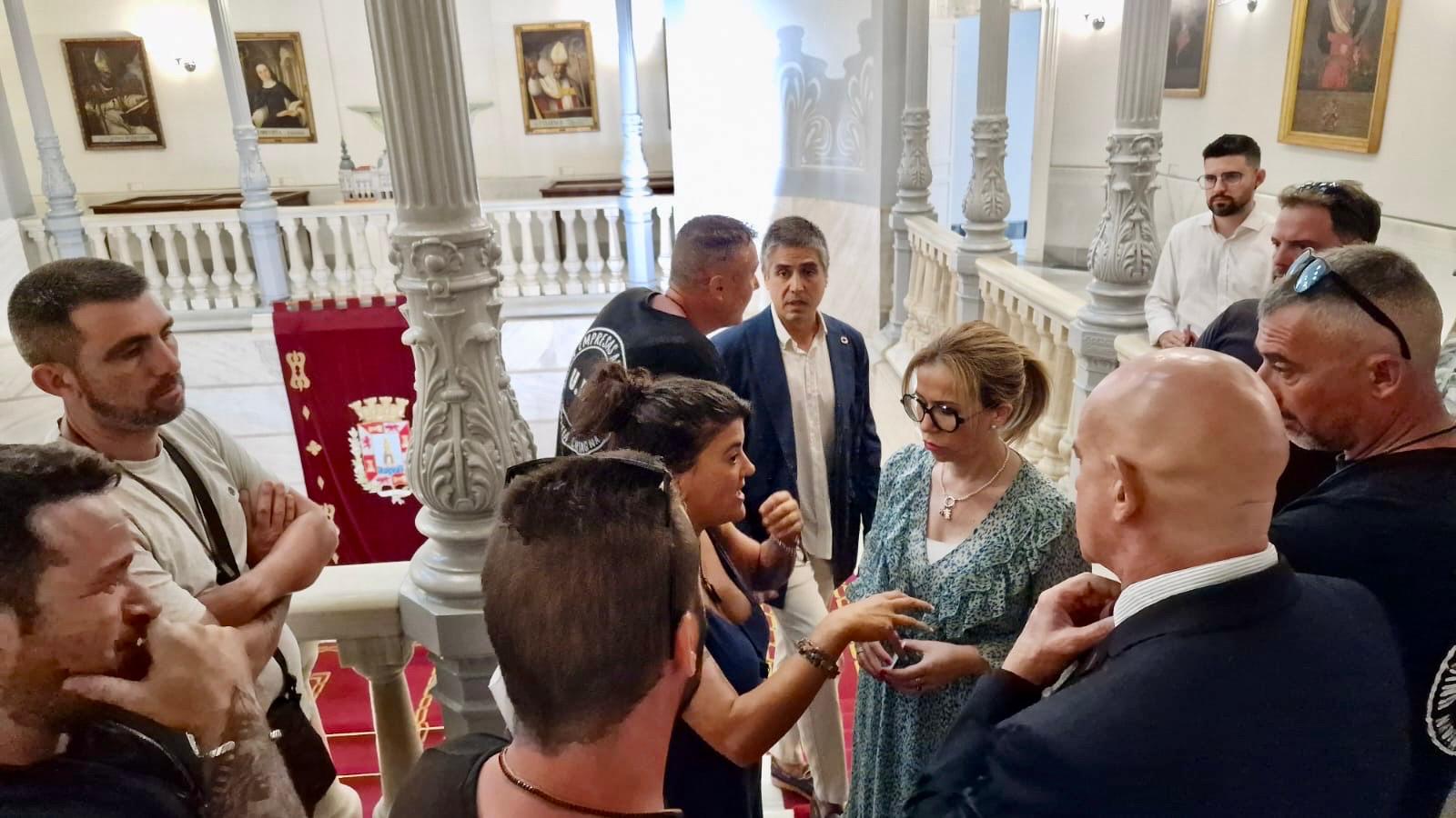 Concejales hablan con los trabajadores del metal en un receso del pleno junto a la escalera principal del Palacio Consistorial