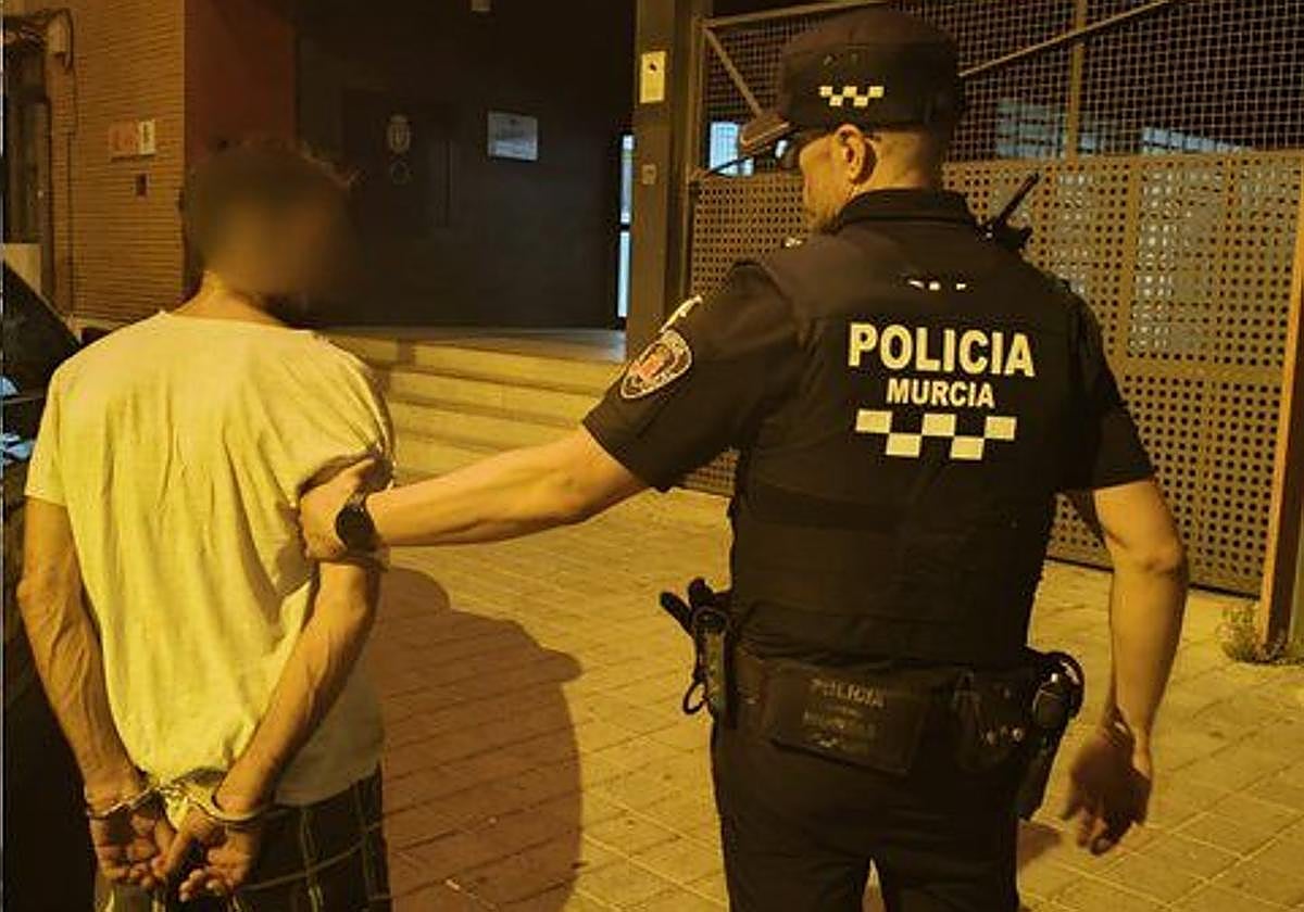 Un agente de la policía junto al detenido.