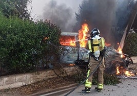 Um bombero apaga las llamas del coche.