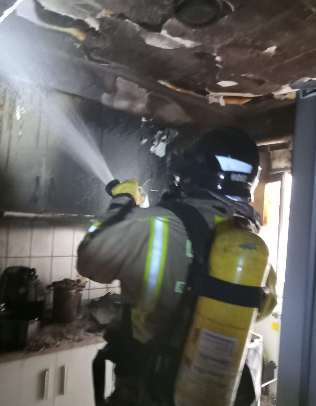 Un bombero refresca la cocina afectada.