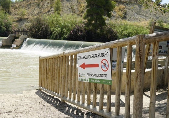 Nuevas señales de la zona prohibida para el baño en El Jarral, con las compuertas de la presa al fondo.