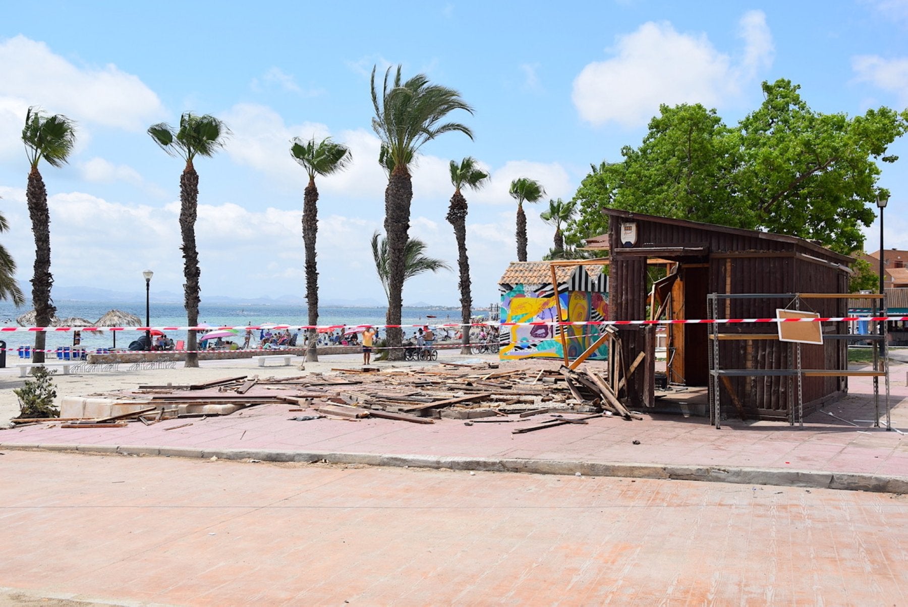 El popular Chinguirito de Los Alcázares, con las tablas en el suelo ante su proceso de desmontaje, este miércoles, junto a la playa llena de bañistas.