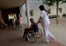 Una sanitaria traslada a una mujer en situación de dependencia en una residencia de Murcia.
