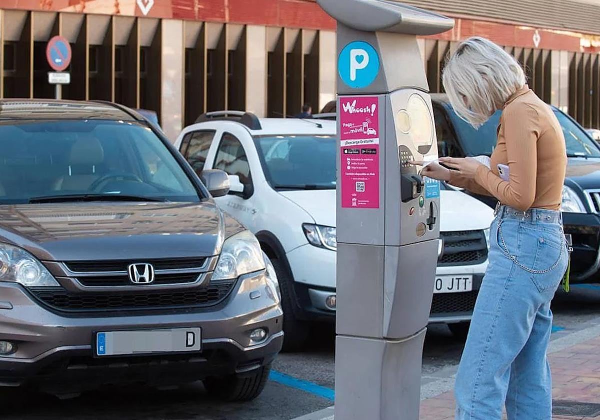 Una joven saca un ticket de zona azul, en una foto de archivo.