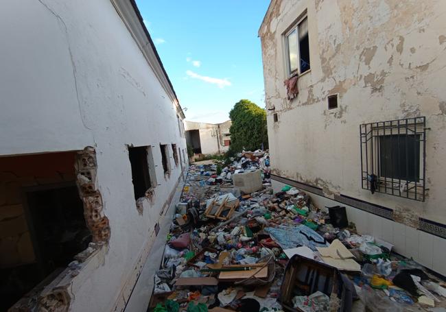 Basura acumulada entre una de las casas okupadas y la nave colindante.