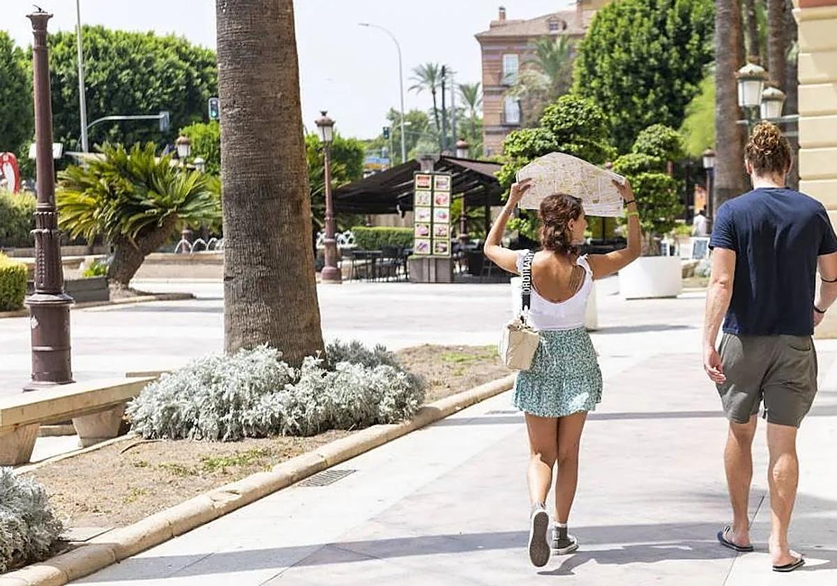 Dos turistas se protegen del calor por las calles de Murcia, en una imagen de archivo.