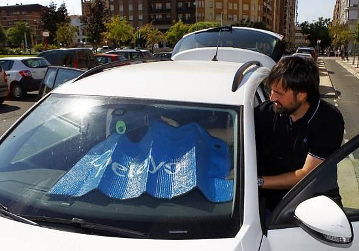 Imagen de archivo de un hombre colocando un parasol en su coche.