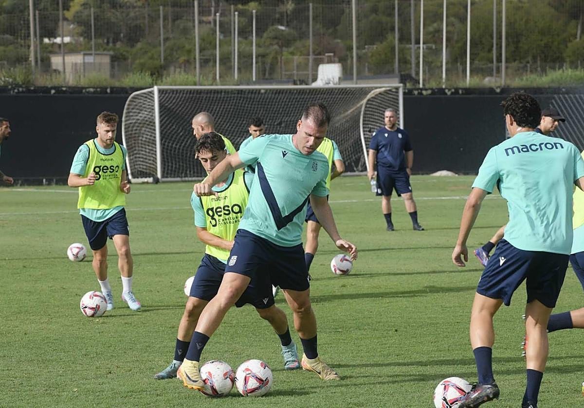 Alfredo Ortuño protege un balón en el entrenamiento de ayer, con el técnico Javi Rey al fondo.