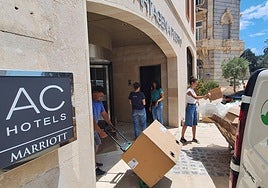 Un grupo de trabajadoras charla distendidamente entre el movimiento de obreros y repartidores a la entrada del hotel por la calle Real.