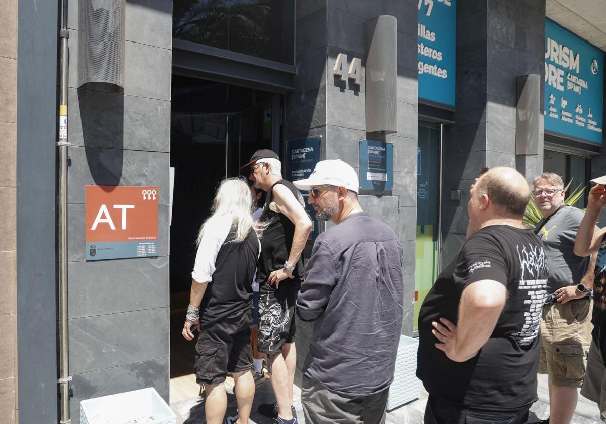 Un grupo de turistas espera para entrar en unos apartamentos turísticos de Cartagena.