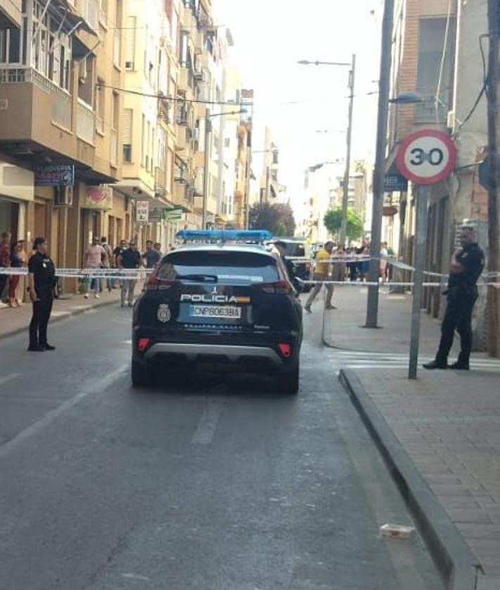 Imagen secundaria 2 - Arriba: Ana Rosell, dueña de la carnicería contigua al local, señala uno de los impactos de bala. Abajo: Fachada del despacho de abogados donde se produjeron los disparos y calle acordonada.