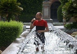Un hombre refrescandose en una fuente durante una ola de calor en Murcia.