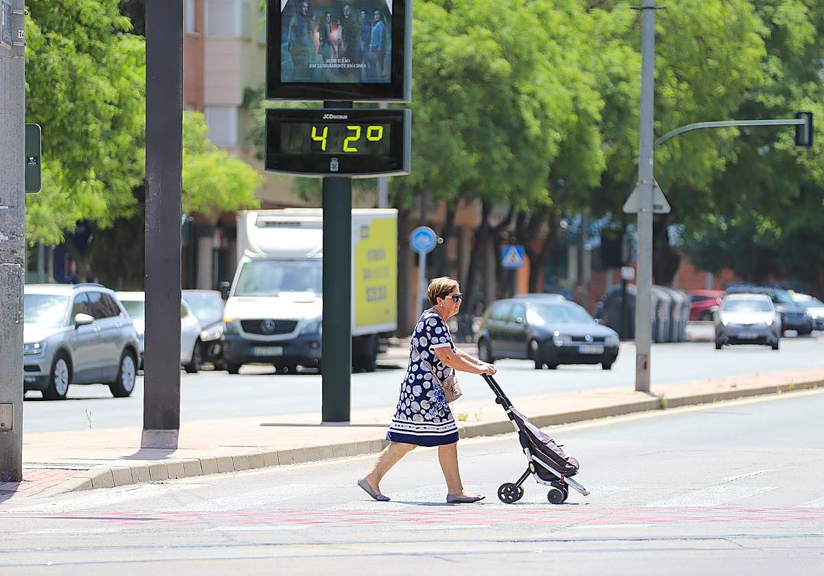 Una mujer pasa junto a un termómetro que marca 42 grados en Murcia, este verano.