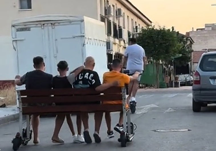 Los cuatro jóvenes sentados en el banco vandalizado.