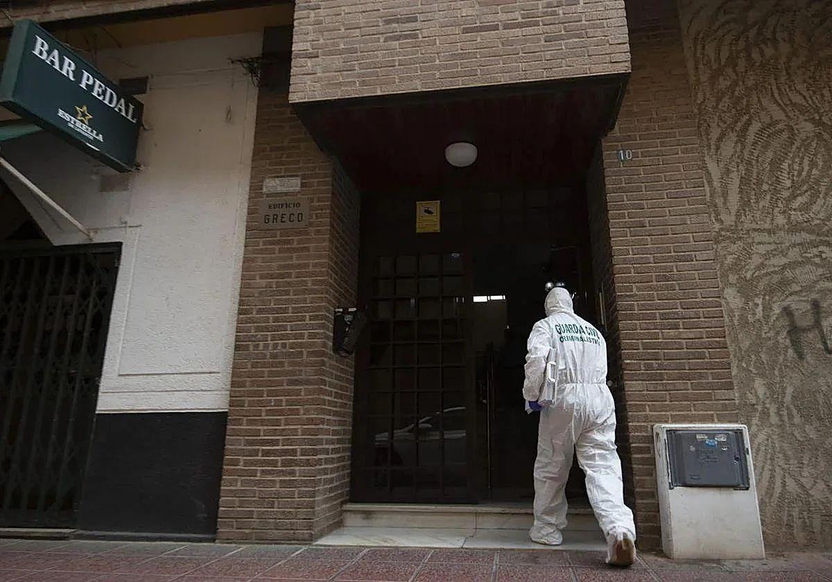 Un agente de la Guardia Civil entra al portal del piso de Cabezo de Torres donde se encontró el cadáver el domingo.