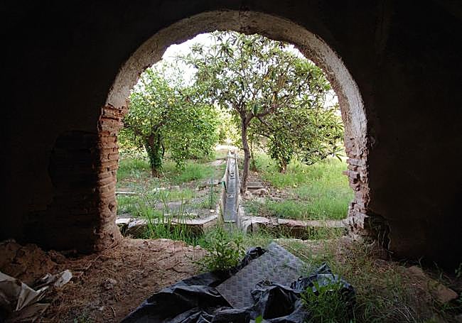 Espacio bajo la escalera que se abre al jardín a través de un arco.