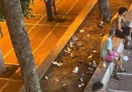 Varias personas en el exterior del local de apuestas con botellas, latas de bebida y vasos a su alrededor.