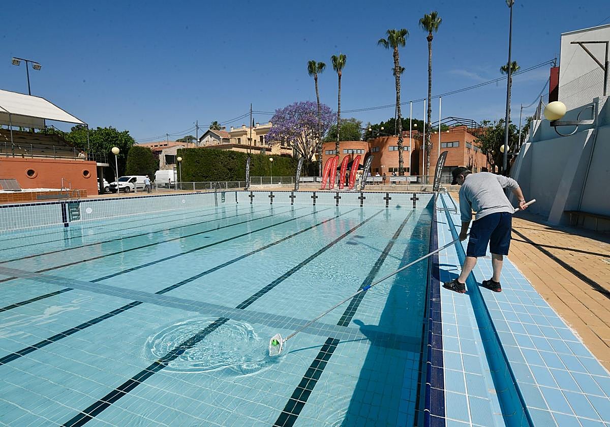 Un trabajador limpia la piscina de Murcia Parque.