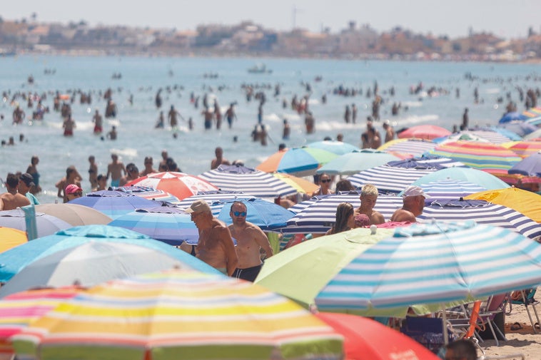 Un mar de sombrillas toma la playa de Las Sirenas, en La Manga, mientras los bañistas se agolpan en el agua para esquivar las altas temperaturas.